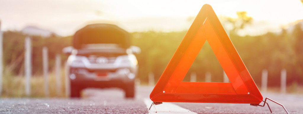 an orange emergency breakdown triangle in the road with a car behind it, bonnet open