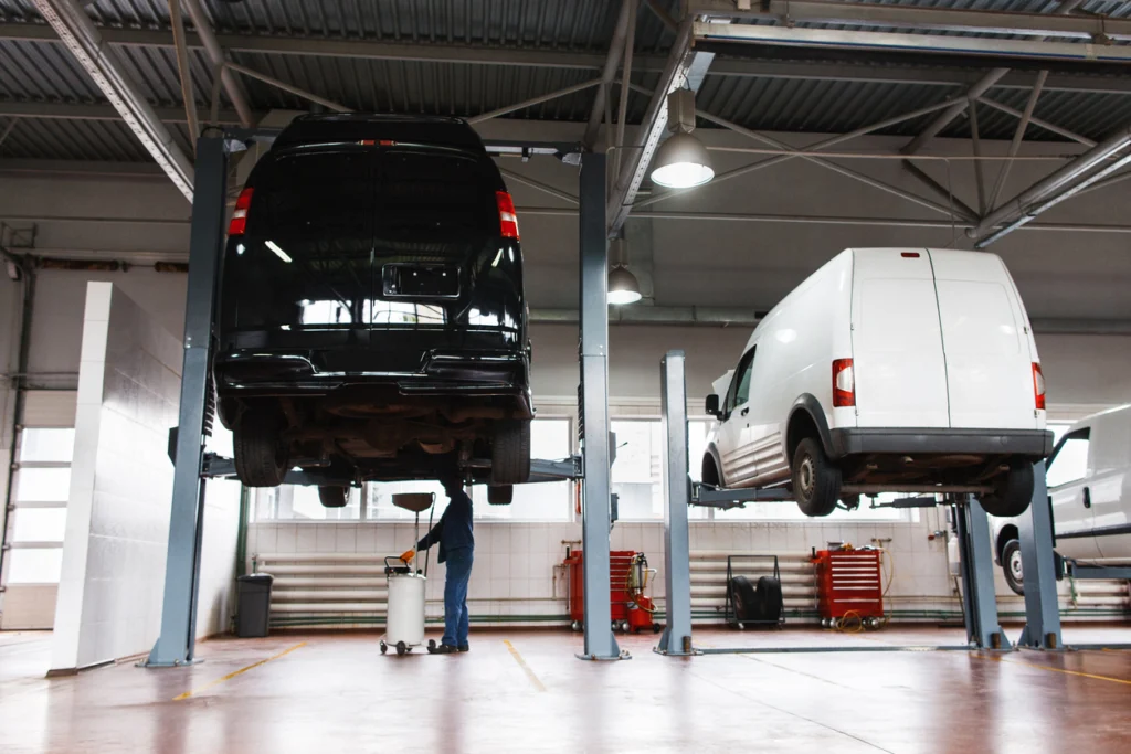Two vans lifted for an MOT at a garage