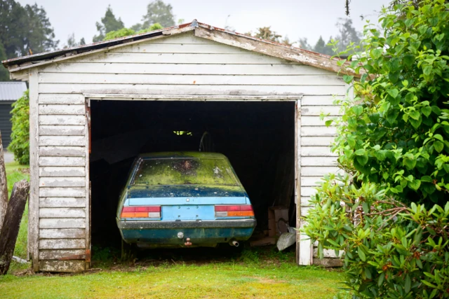 A car that has been left for a while in a garage in need of repair